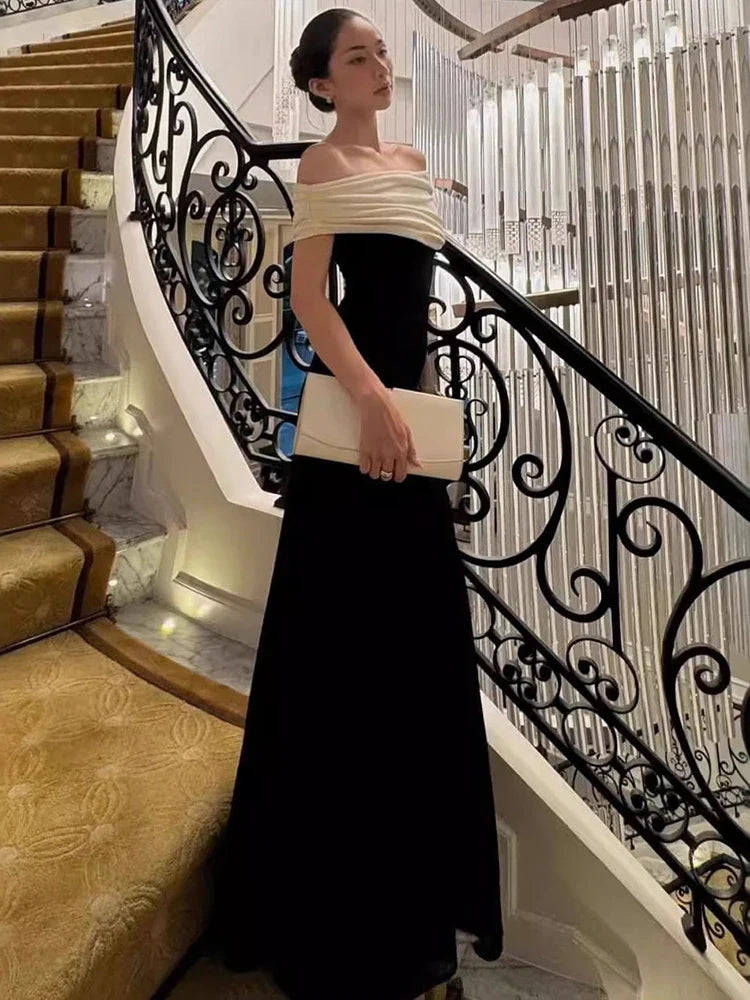 Woman in a black and white dress standing on a staircase with decorative railings.