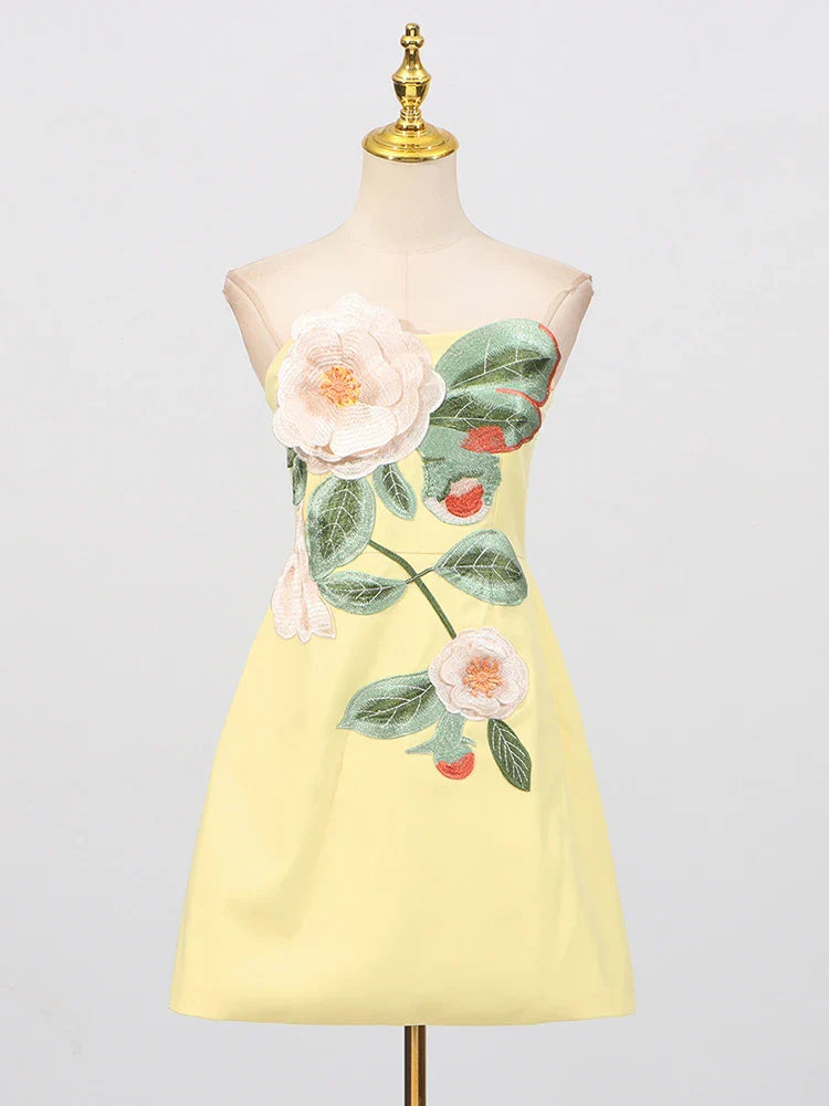 Yellow dress with floral design on a mannequin against a light gray background