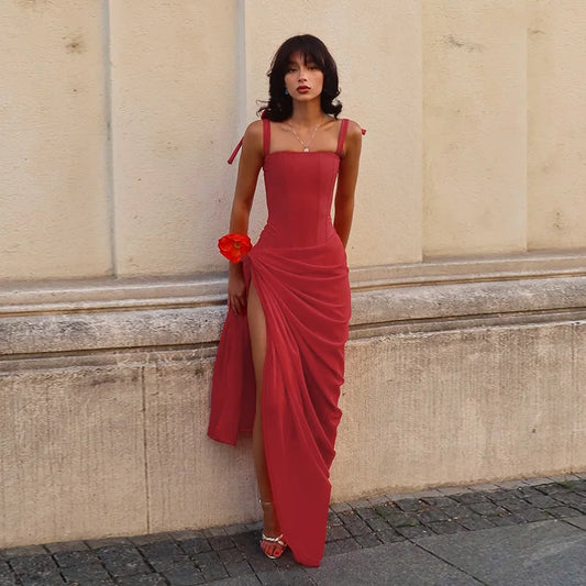 Woman in a red dress standing against a beige wall.
