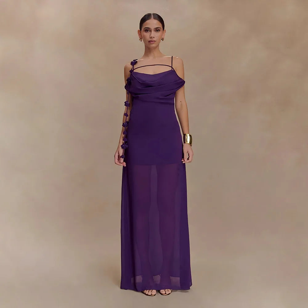Woman wearing a long purple dress with floral details on a beige background