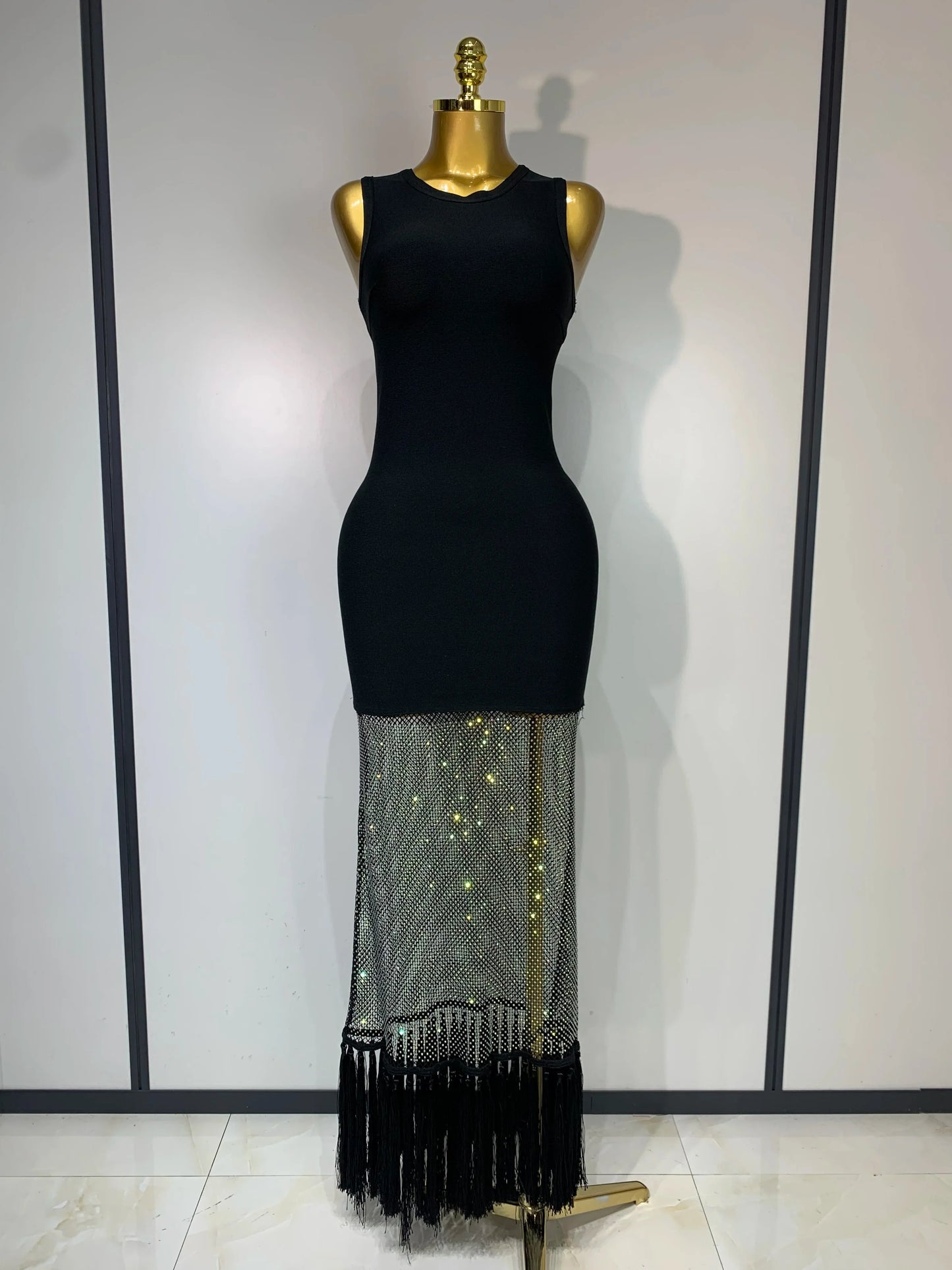 Black dress with a sheer, fringed bottom section on a mannequin against a white background