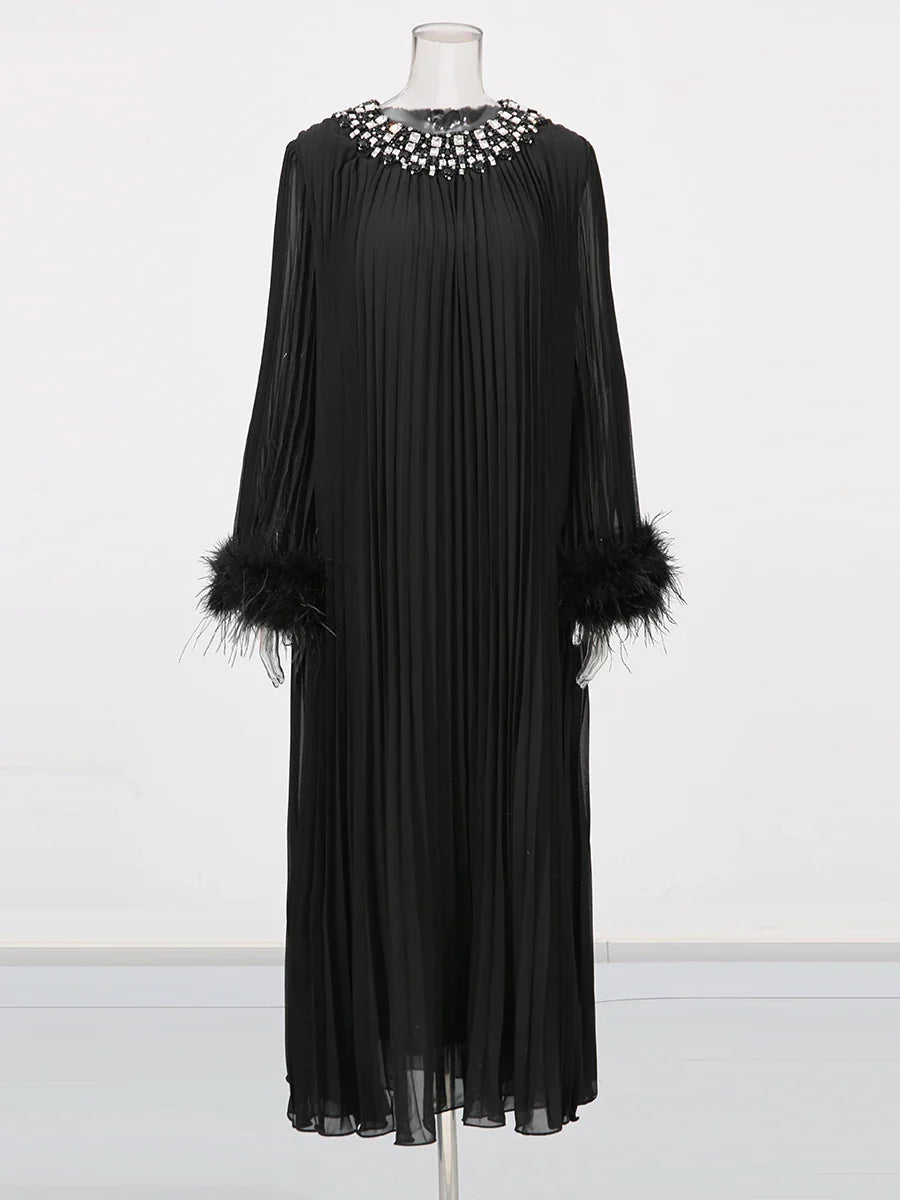 Black dress with feathered sleeves on a mannequin against a white background