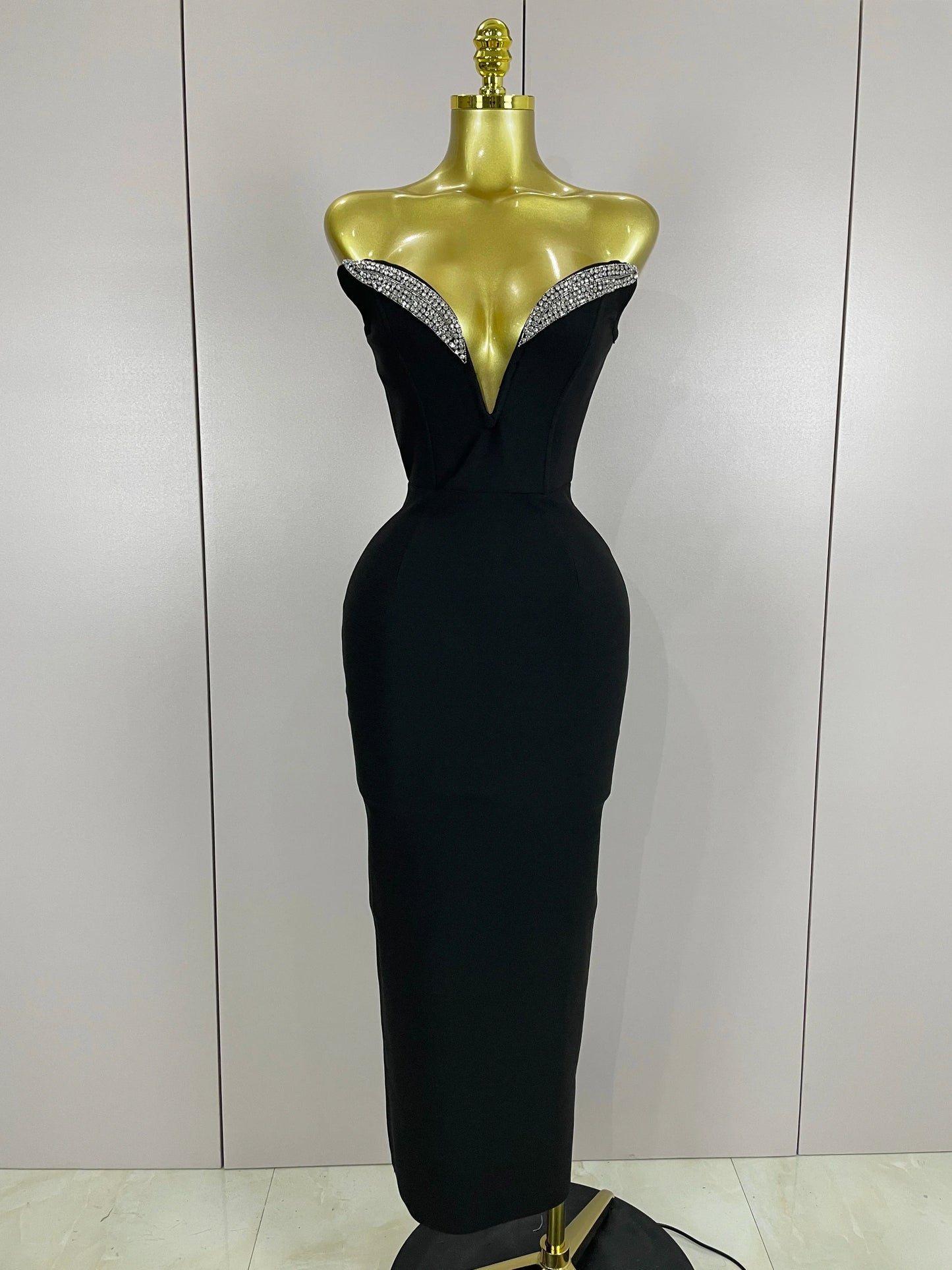Black evening gown with beaded neckline on a mannequin against a plain background