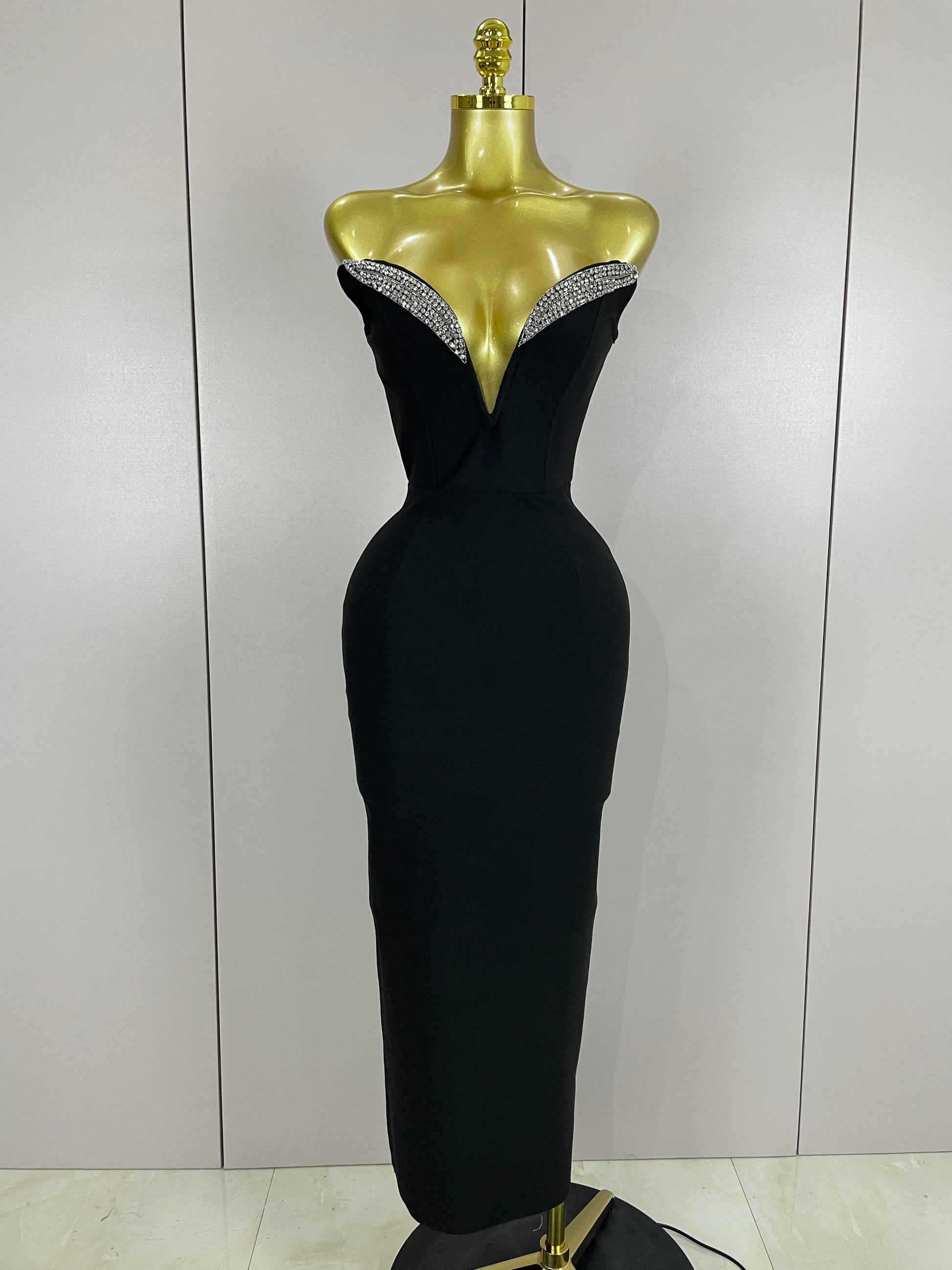Black evening gown with beaded neckline on a mannequin against a plain background
