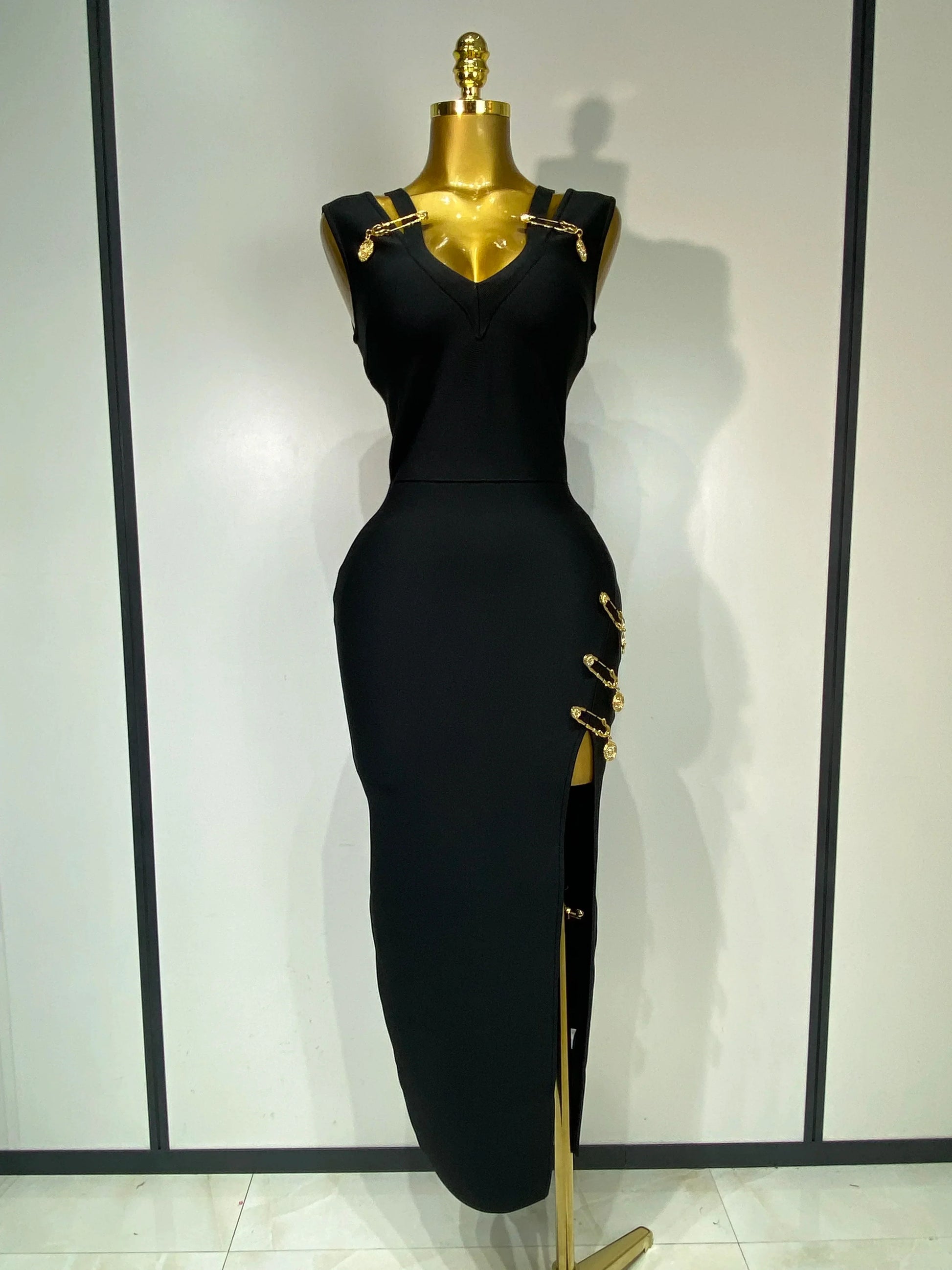 Black dress with gold accents on a mannequin against a white background