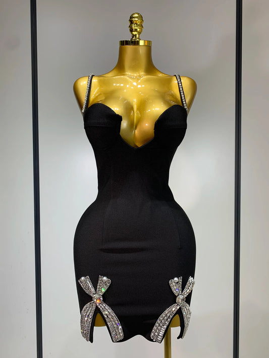 Black dress with decorative bows on a gold mannequin against a neutral background