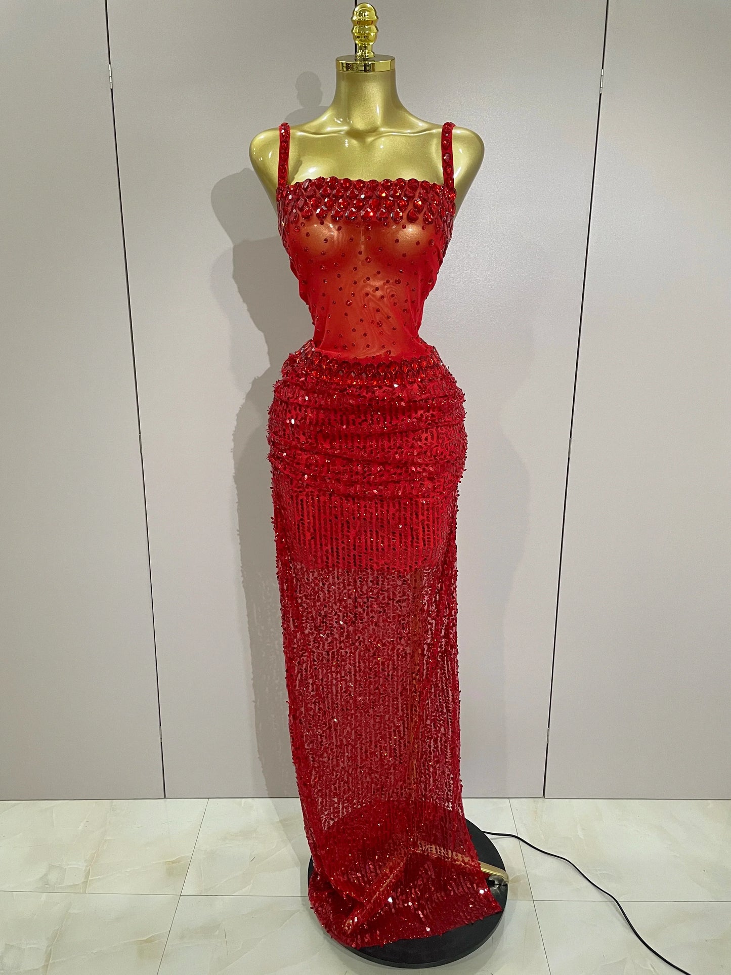 Red beaded evening gown on a mannequin against a plain background