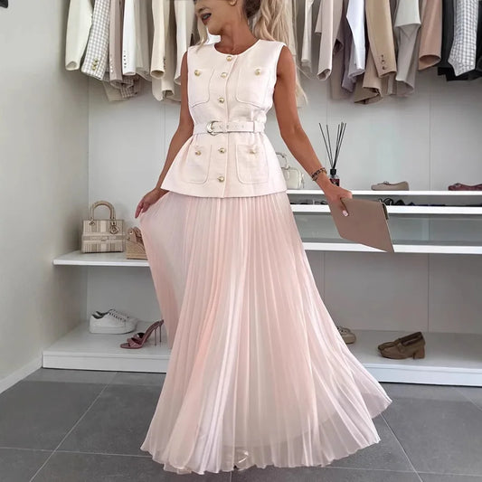 Woman wearing a white sleeveless top with buttons and a long light pink pleated skirt in a clothing store.