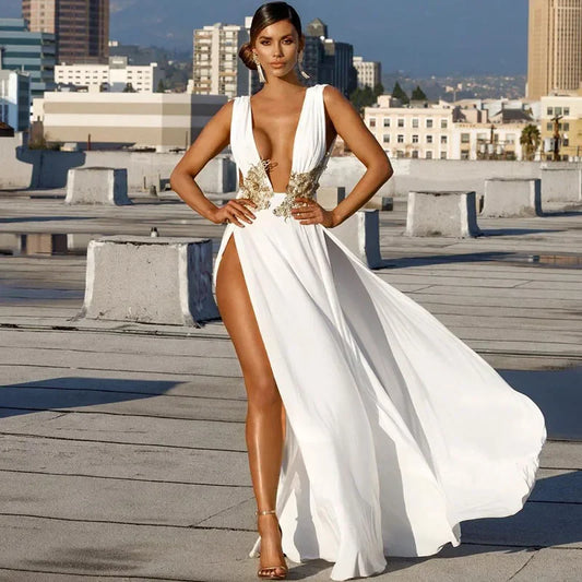 Woman in a white gown with gold accents on a rooftop with cityscape background