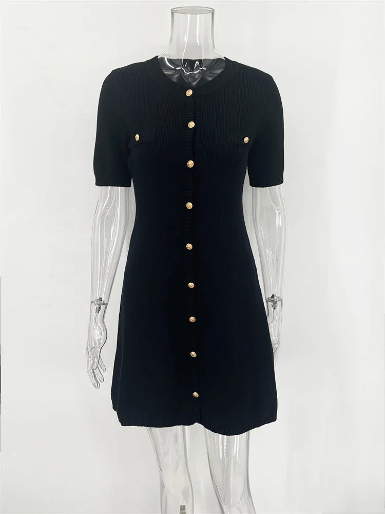 Black dress with gold buttons on a mannequin against a white background