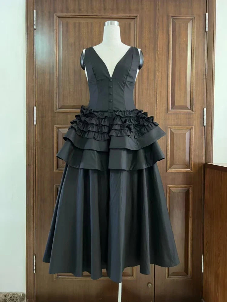 Black dress with ruffled layers on a mannequin against a wooden door background