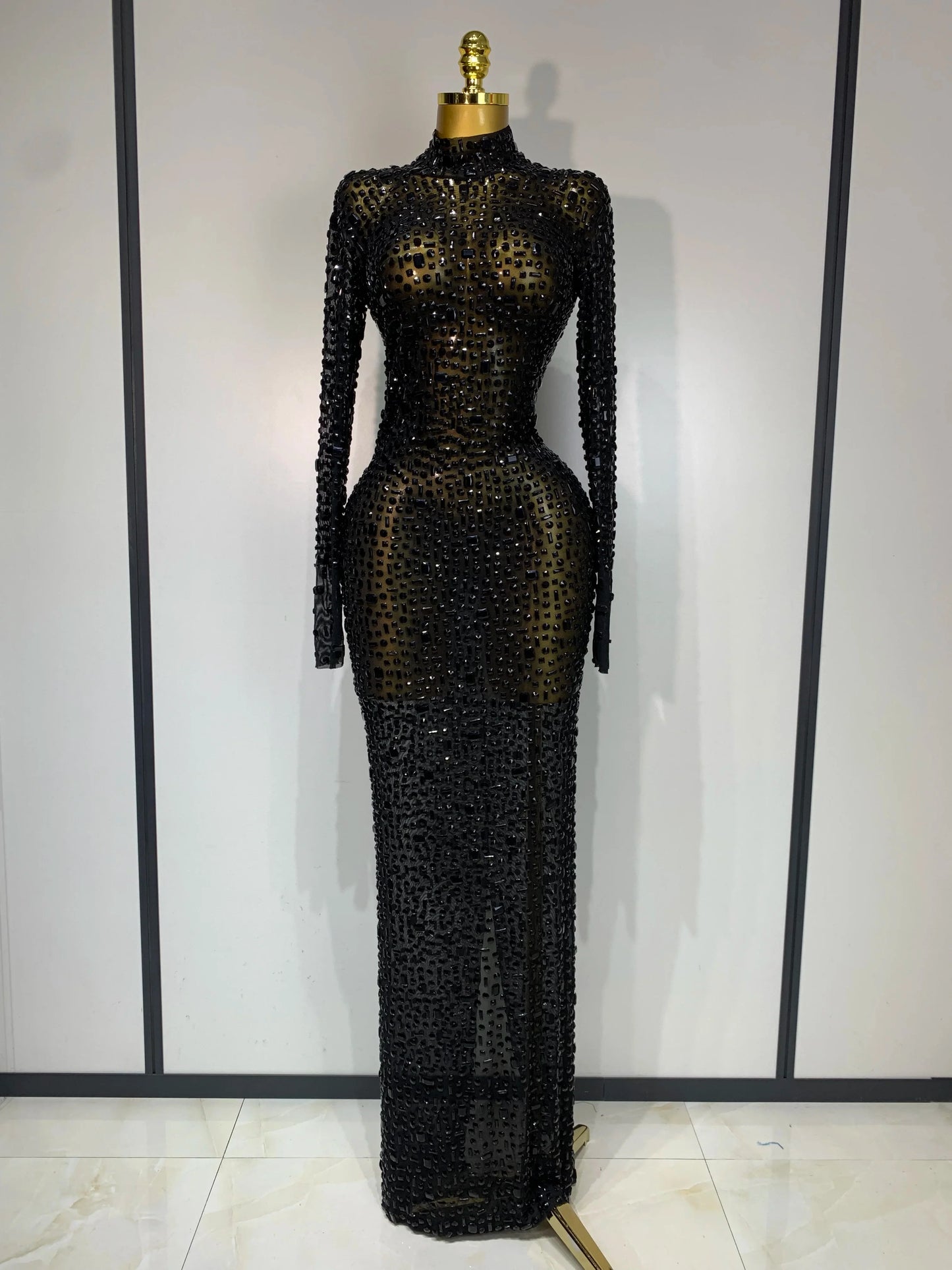 Black beaded evening gown on a mannequin against a plain background