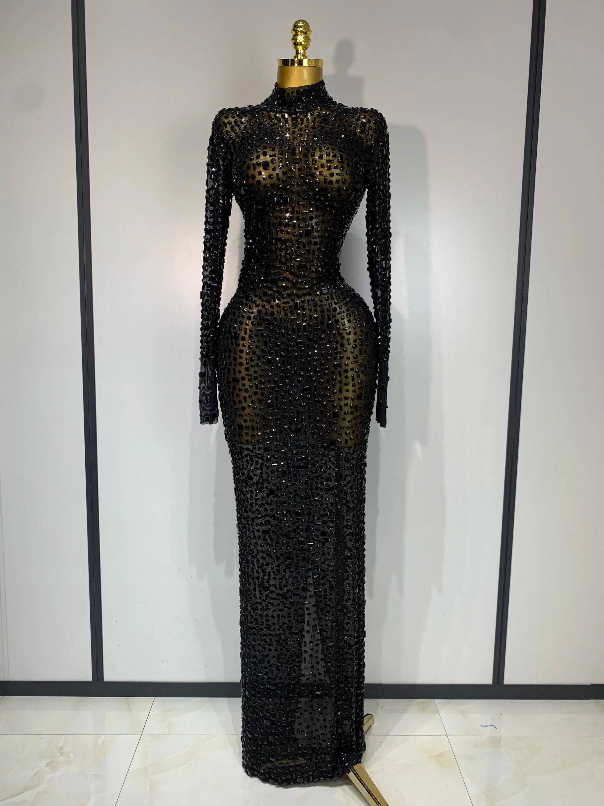 Black beaded evening gown on a mannequin against a plain background