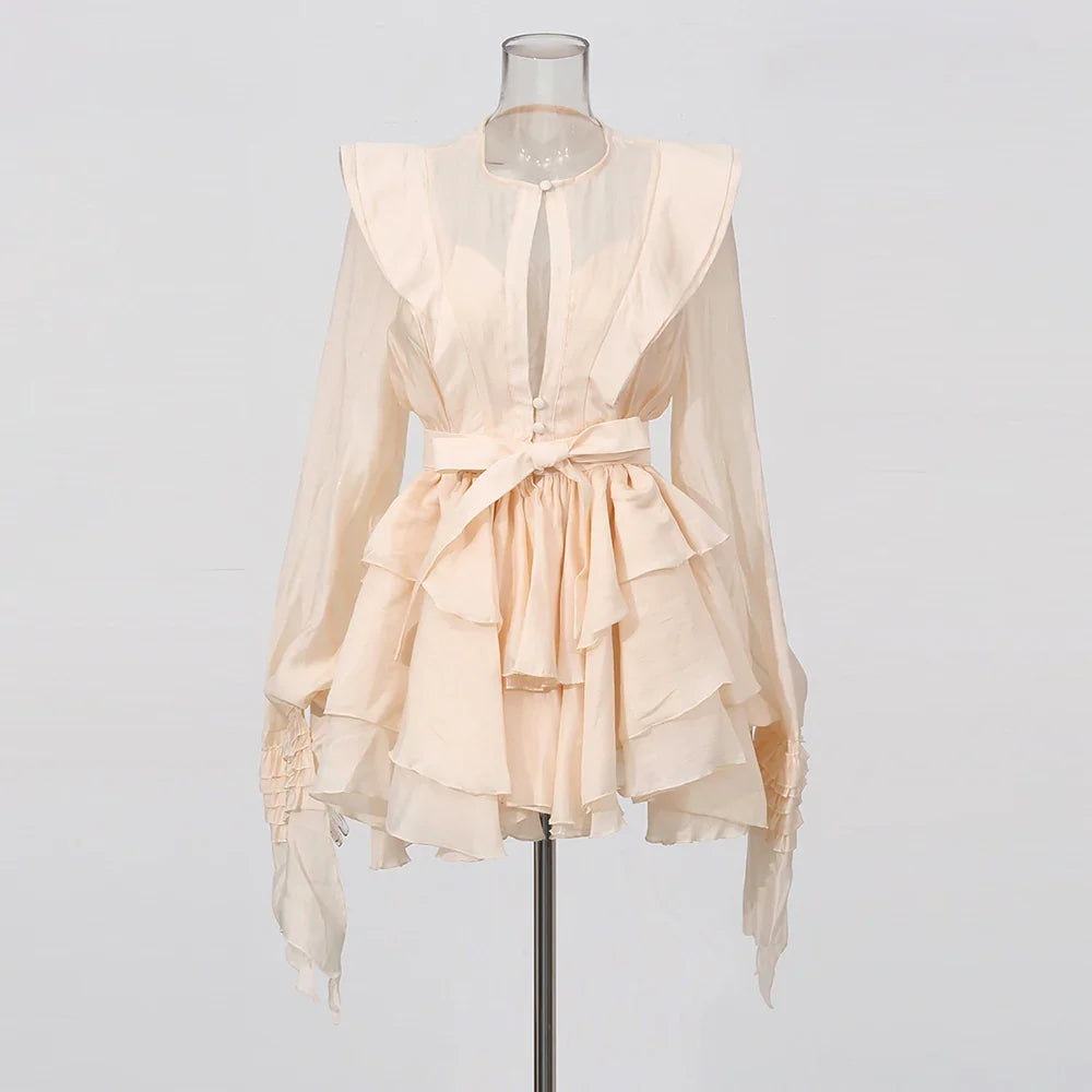 Beige ruffled blouse on a mannequin against a plain background