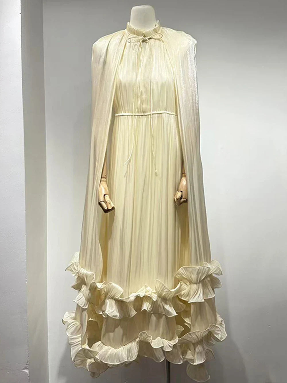 Mannequin wearing a cream-colored dress with ruffled skirt against a gray background
