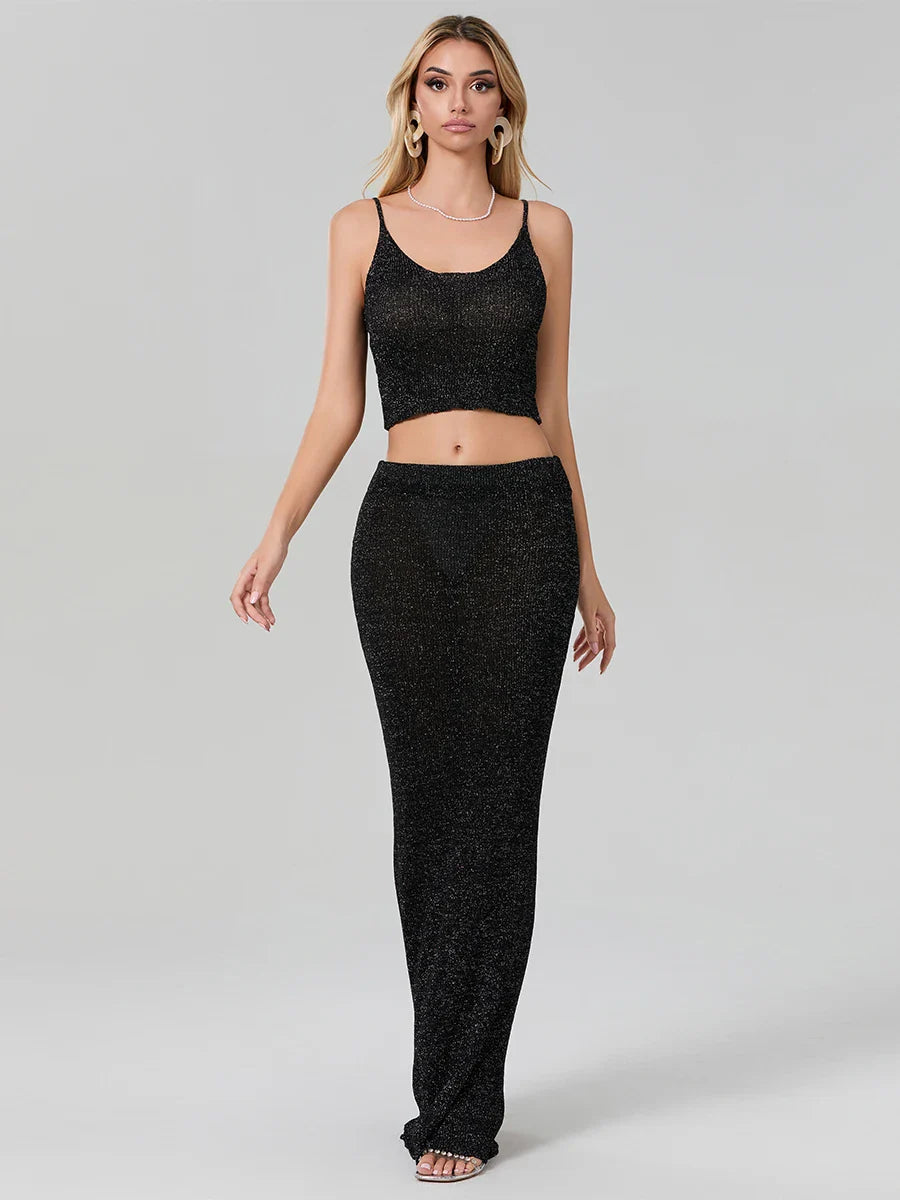 Woman wearing a black sparkly top and pants on a gray background