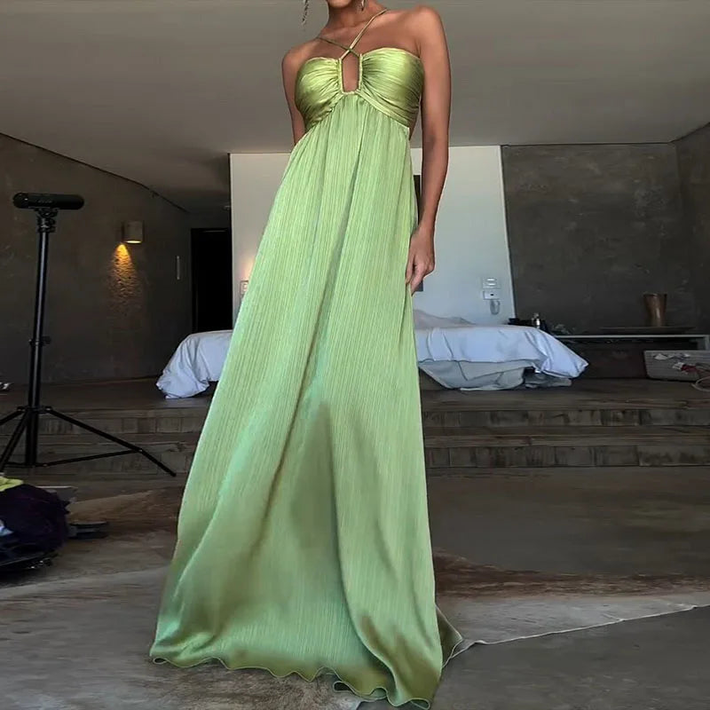 Person wearing a long green dress in a room with a bed and lamp.