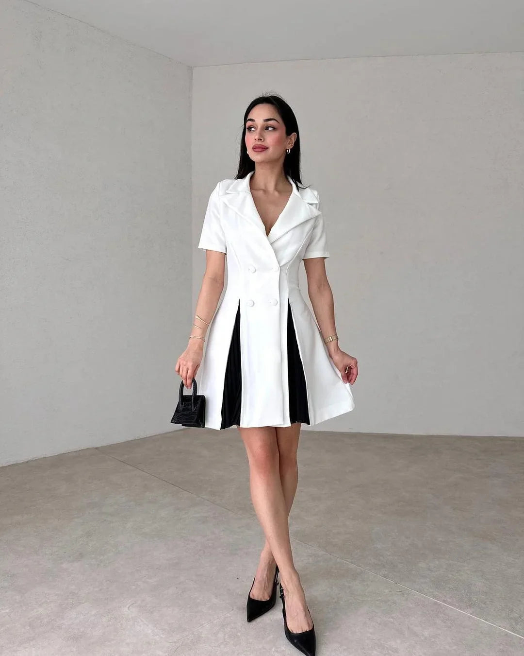 Woman wearing a white dress with black accents in a minimalistic setting