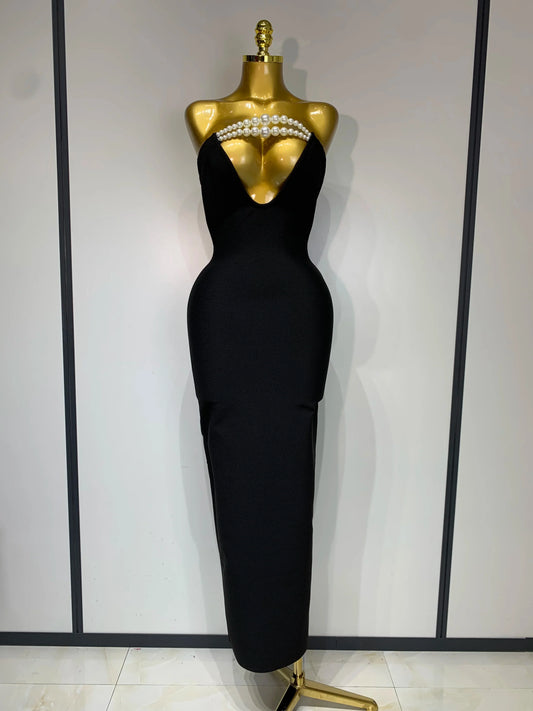 Black evening gown on a mannequin with pearl embellishments against a white background