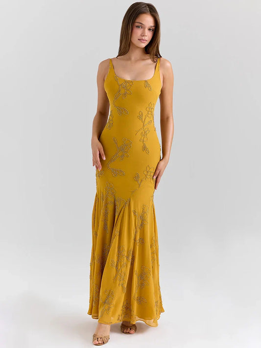 Woman wearing a mustard yellow dress with floral patterns on a white background