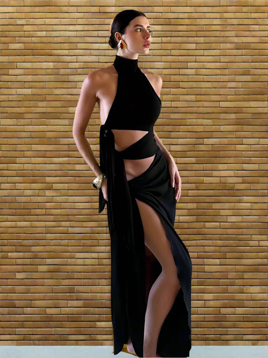 A woman wearing a black hollow-out high split maxi party dress styled for a club night in a room with a brick wall.