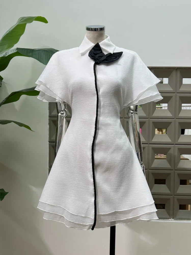 Feminine cocktail mini with contrast edging and fitted waist and black accents on a mannequin against a neutral background