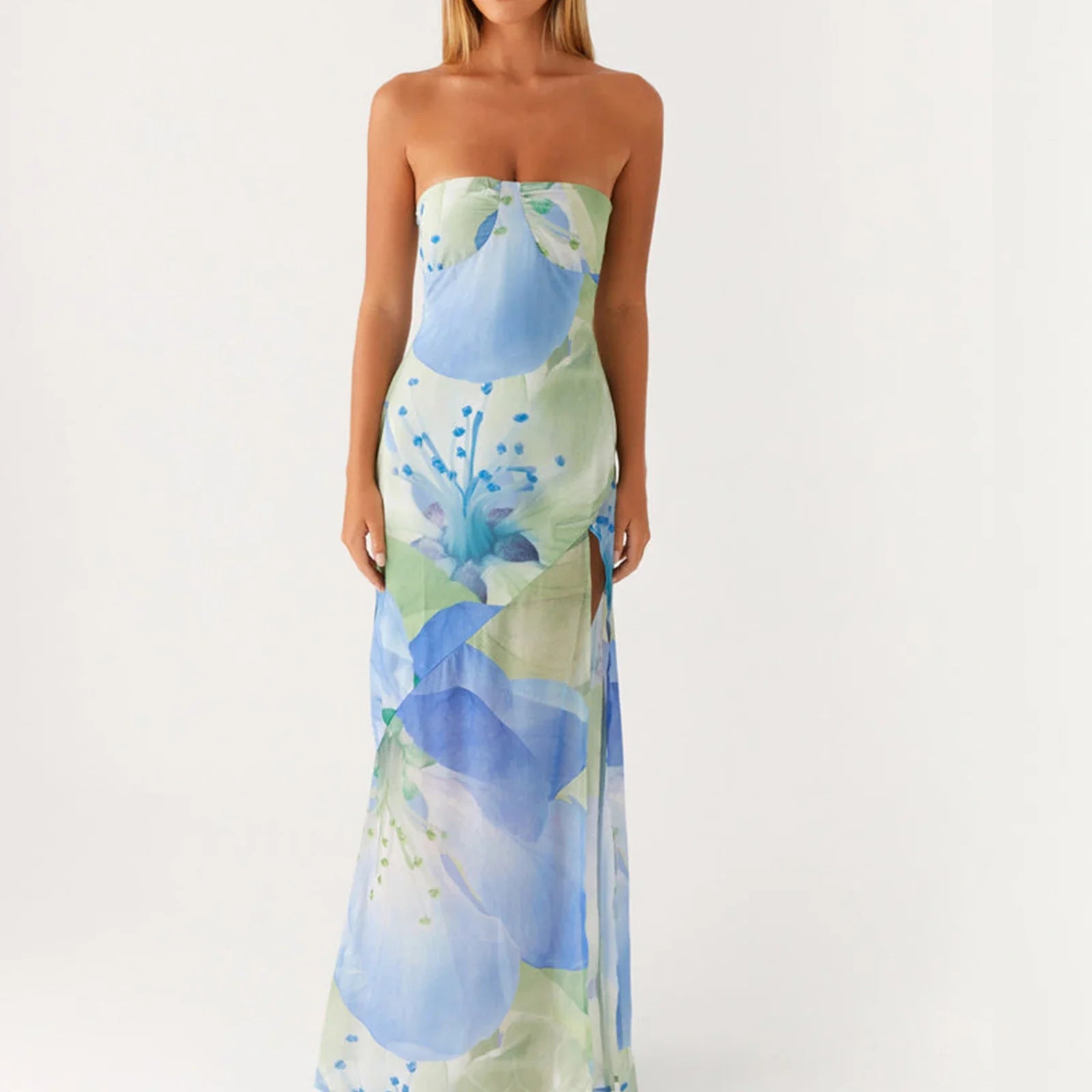 Woman in strapless blue floral maxi dress with side slit standing against white background