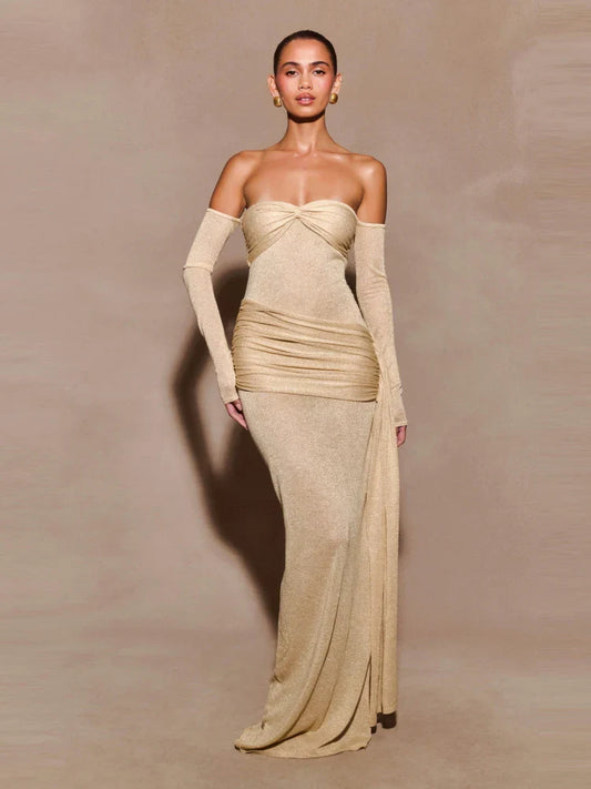 A woman wearing a strapless beige draped evening gown with a sculpted fit on a plain background