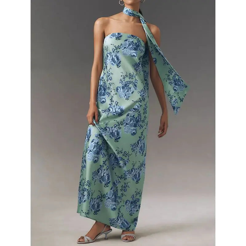 Woman wearing a strapless floral satin dress styled for summer evenings with a matching scarf on a neutral background