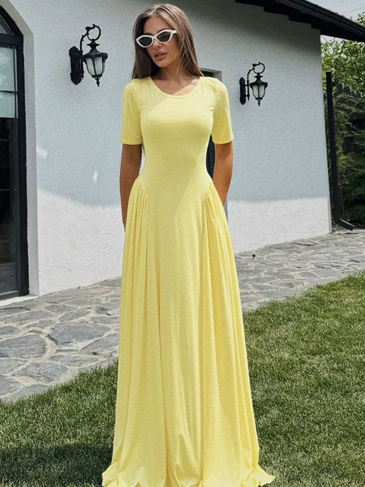 Woman in yellow short sleeve maxi dress standing on a stone path